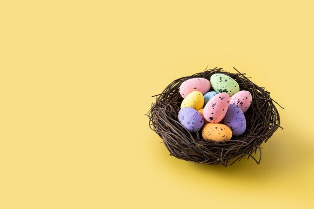 Coloridos huevos de Pascua dentro de un nido sobre fondo amarillo Copiar espacio