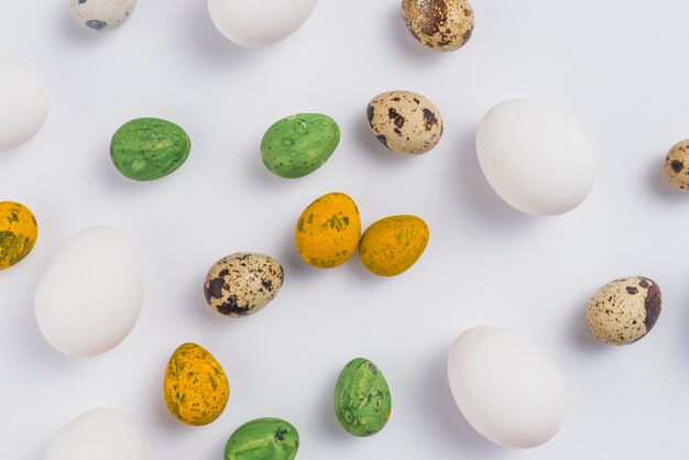 Coloridos huevos de Pascua dispersos en mesa blanca