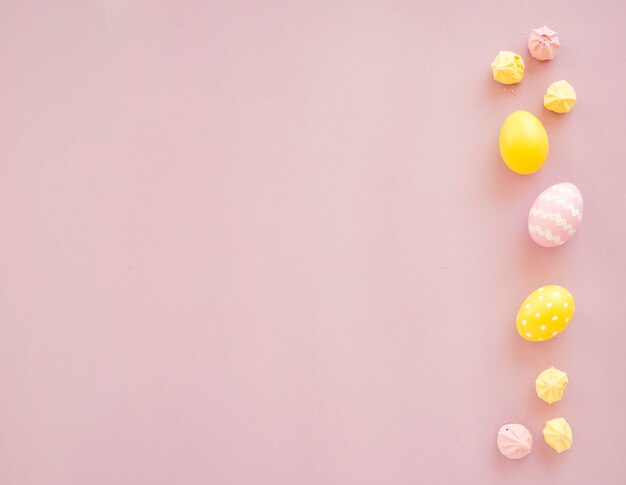 Coloridos huevos de Pascua con dulces en mesa