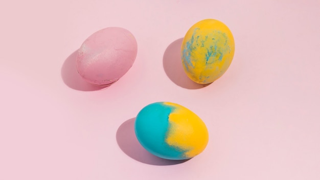 Coloridos huevos de Pascua esparcidos sobre mesa rosa