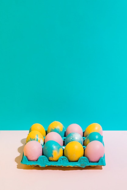 Foto gratuita coloridos huevos de pascua en estante brillante en mesa rosa