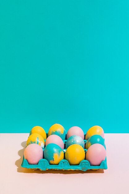 Coloridos huevos de Pascua en estante brillante en mesa rosa