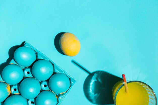 Coloridos huevos de Pascua en estante con pincel en vaso de agua