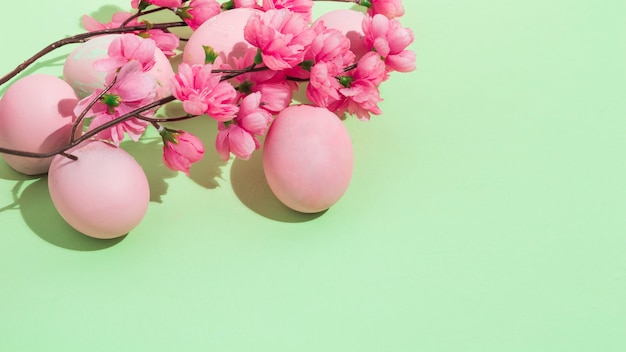 Coloridos huevos de Pascua con flores en mesa verde
