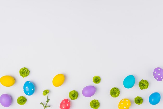 Coloridos huevos de Pascua con flores en la mesa