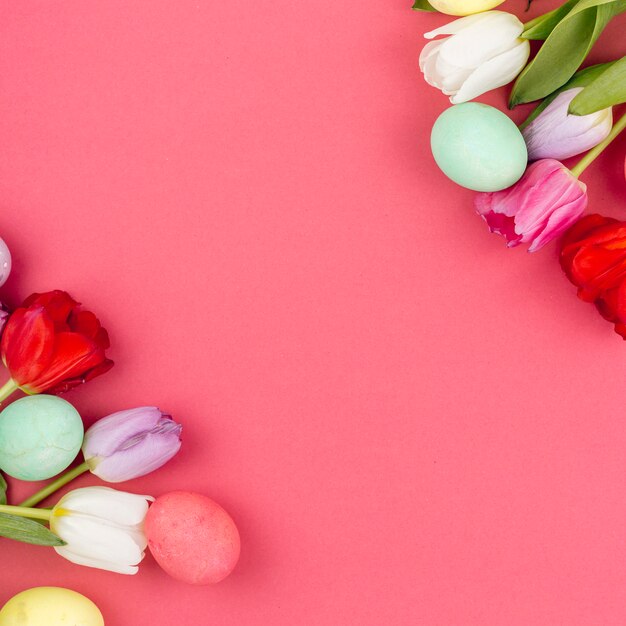 Coloridos huevos de Pascua con flores de tulipán en mesa