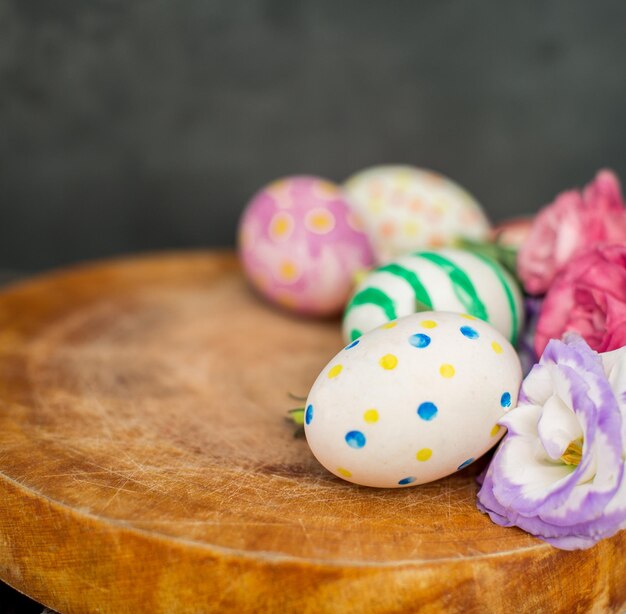 Coloridos huevos de pascua y lisianthus en mesa de madera