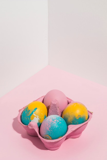 Coloridos huevos de Pascua en pequeño estante en mesa