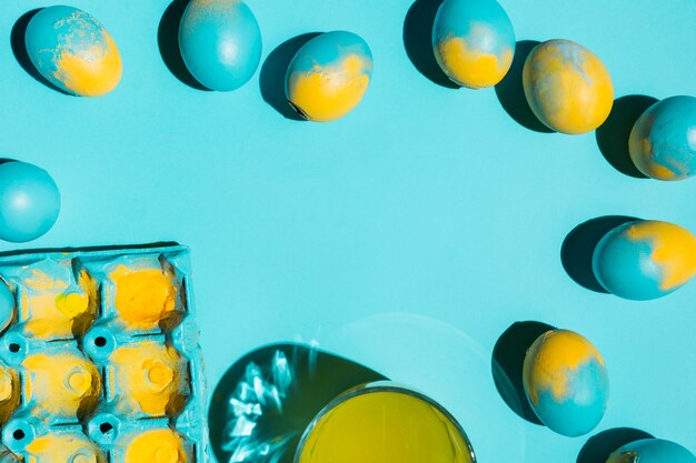 Coloridos huevos de pascua con perchero y vaso de agua.