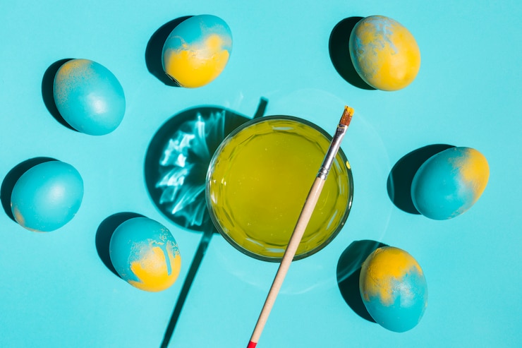 Foto gratuito coloridos huevos de pascua con pincel y vaso de agua sobre mesa