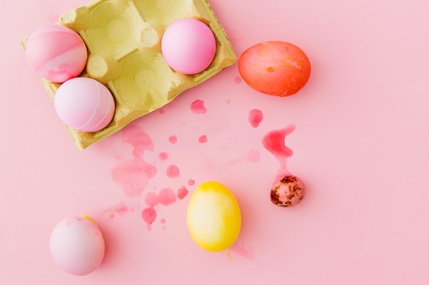 Coloridos huevos de Pascua en un recipiente entre salpicaduras de líquido tinte.