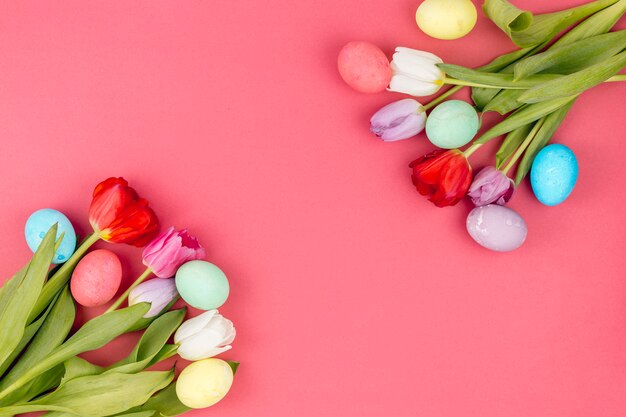 Coloridos huevos de Pascua con tulipanes en mesa