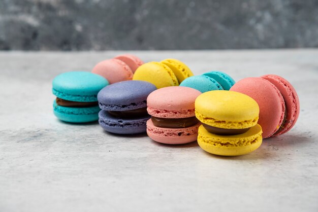 Coloridos macarons de almendra pastel en mesa blanca.