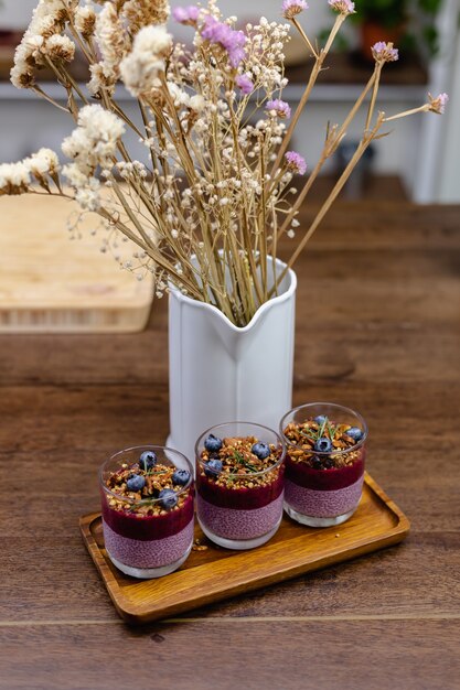 Coloridos postres dulces de desayuno saludable algunos diferentes budines de chia en frascos de vidrio sobre la mesa de madera en la cocina de casa.