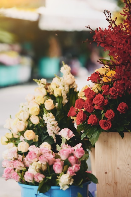 Coloridos racimos de rosas frescas que se muestran en cubos fuera de la florería