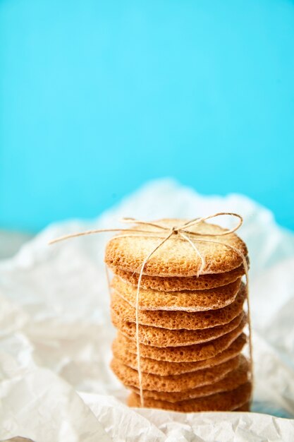 Columna de sabrosas galletas atadas con cuerda para regalo sobre fondo turquesa