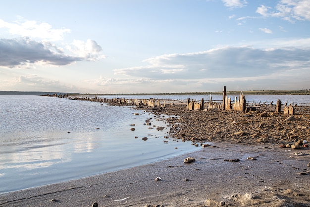 Columnas de madera cubiertas de sal sobresalen del agua de la desembocadura del Kuyalnik al atardecer