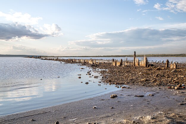 Columnas de madera cubiertas de sal sobresalen del agua de la desembocadura del Kuyalnik al atardecer