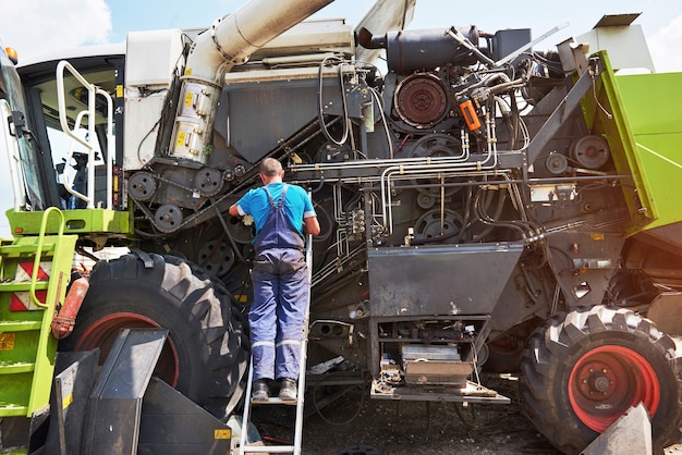 Combine el servicio de la máquina, el mecánico repara el motor al aire libre.