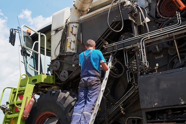 Foto gratuita combine el servicio de la máquina, el mecánico repara el motor al aire libre.