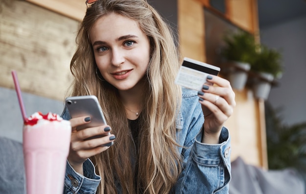 Comer fuera y concepto de gente sincera. Joven mujer rubia pagando f