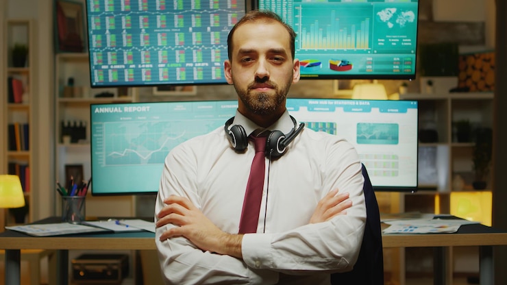 Foto gratuito comerciante de bolsa con barba mirando a la cámara con las manos cruzadas.