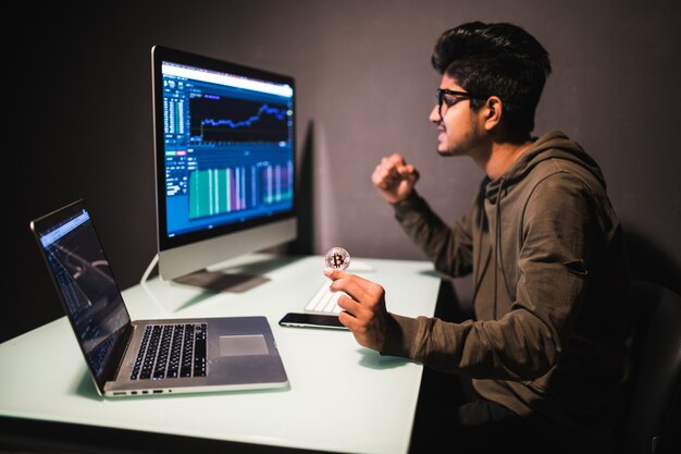 Comerciante indio con bitcoin comprobando el concepto de análisis de datos de comercio de acciones trabajando en la oficina con gráfico financiero en monitores de computadora
