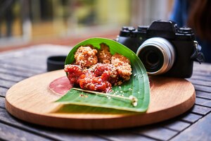 Foto gratis comida asiática tradicional envuelta en hojas de bambú en un plato de madera con una cámara fotográfica cerca.