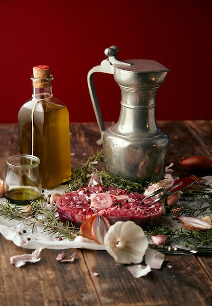 Comida: cebollas, romero, filete de carne, sal, pimienta, ajo, aceite de oliva, tenedor, salsas.