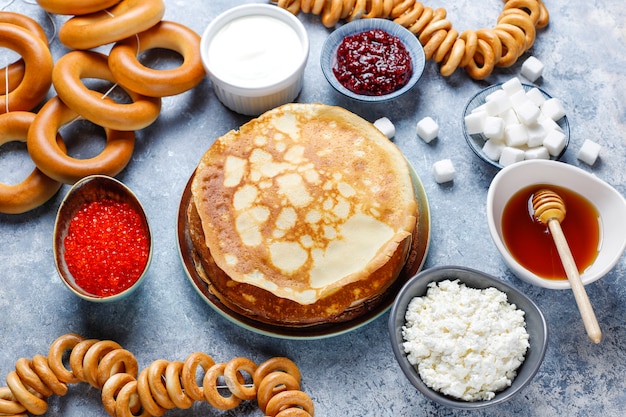 Comida del festival Shrovetide Maslenitsa. Panqueque ruso blini con mermelada de frambuesa, miel, crema fresca y caviar rojo, terrones de azúcar, requesón a la luz