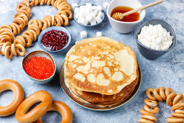 Comida del festival Shrovetide Maslenitsa. Panqueque ruso blini con mermelada de frambuesa, miel, crema fresca y caviar rojo, terrones de azúcar, requesón a la luz