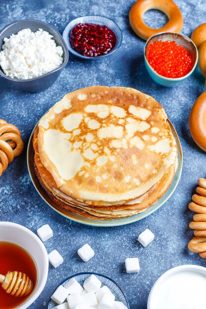 Comida del festival Shrovetide Maslenitsa. Panqueque ruso blini con mermelada de frambuesa, miel, crema fresca y caviar rojo, terrones de azúcar, requesón oscuro