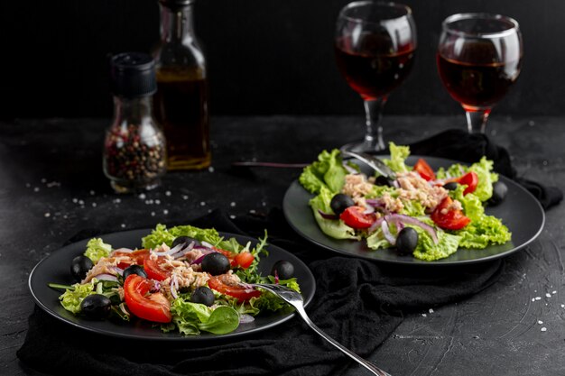 Comida fresca de alto ángulo con vajilla oscura y copas de vino