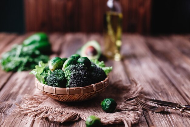 Comida fresca y saludable. Cuenco de madera con brócoli, coles de bruselas, aceite de oliva, pimiento verde