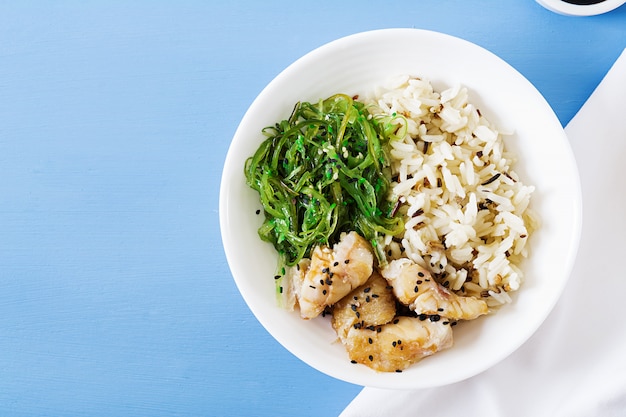 Comida japonesa. Tazón de arroz, pescado blanco hervido y ensalada de wakame chuka o algas. Vista superior. Lay Flat