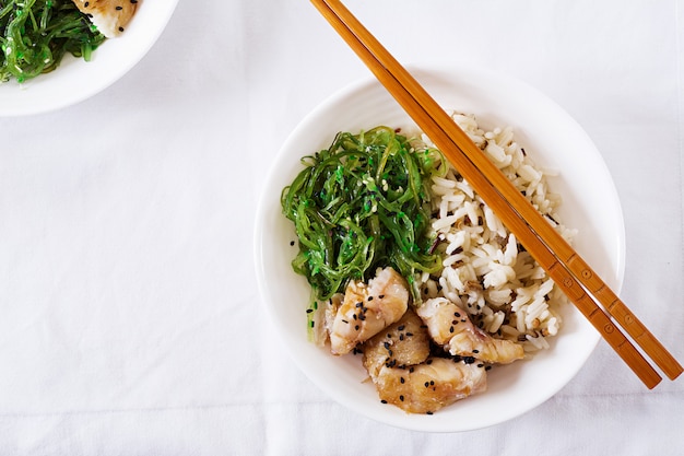 Comida japonesa. Tazón de arroz, pescado blanco hervido y ensalada de wakame chuka o algas. Vista superior. Lay Flat