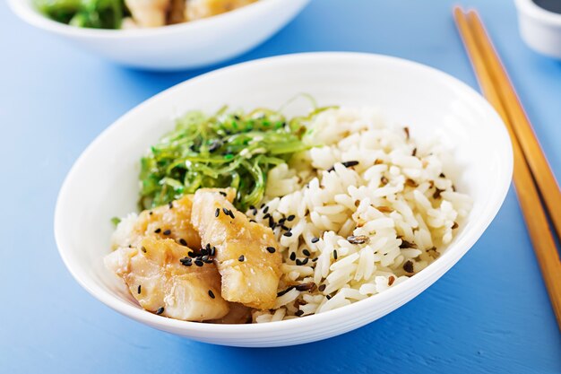 Comida japonesa. Tazón de arroz, pescado blanco hervido y ensalada de wakame chuka o algas.