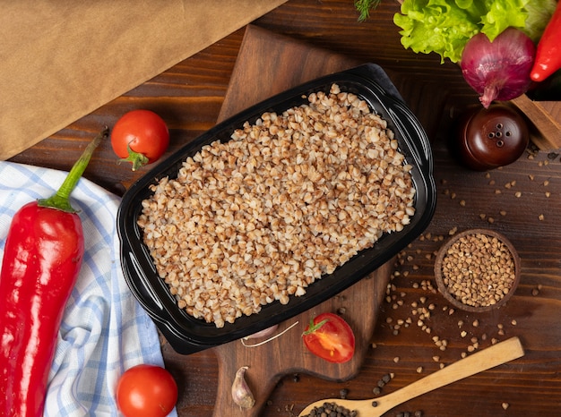 Comida para llevar del alforfón en el envase de plástico negro, alimento dietético.