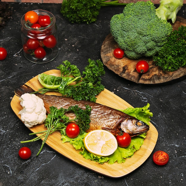 Comida mediterránea, pescado de arenque ahumado servido con cebolla verde, limón, tomates cherry, especias, pan y salsa Tahini.