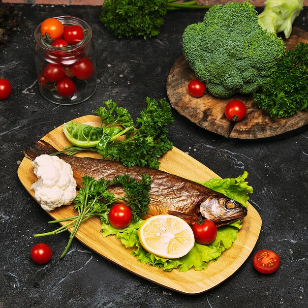 Comida mediterránea, pescado de arenque ahumado servido con cebolla verde, limón, tomates cherry, especias, pan y salsa Tahini.