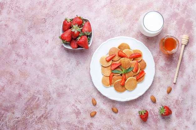 Comida de moda: mini cereal para panqueques. Montón de panqueques de cereales con bayas y nueces.