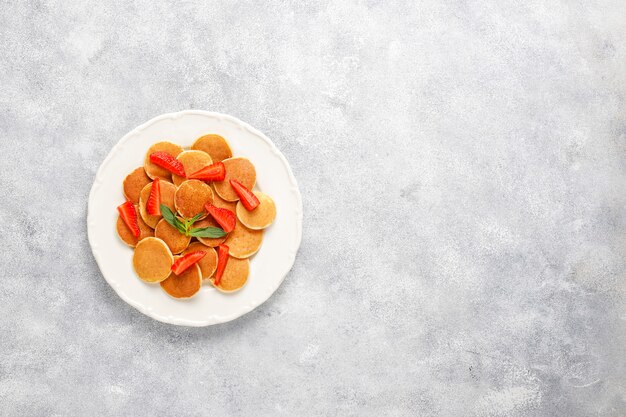 Comida de moda: mini cereal para panqueques. Montón de panqueques de cereales con bayas y nueces.