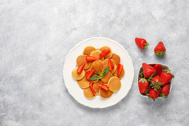 Comida de moda: mini cereal para panqueques. Montón de panqueques de cereales con bayas y nueces.