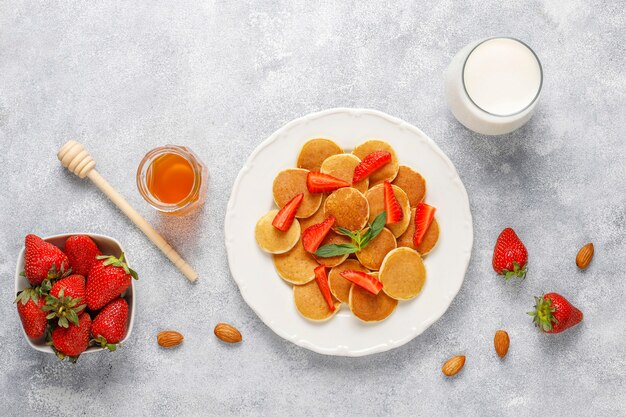 Comida de moda: mini cereal para panqueques. Montón de panqueques de cereales con bayas y nueces.