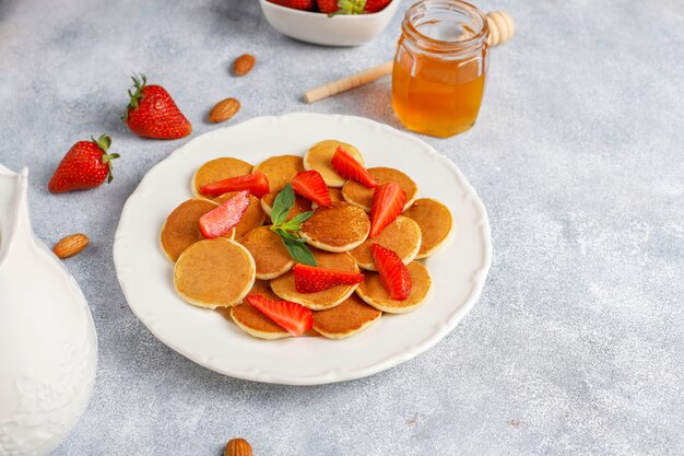 Comida de moda: mini cereal para panqueques. Montón de panqueques de cereales con bayas y nueces.