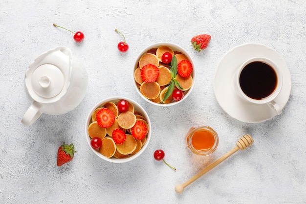 Comida de moda: mini cereal para panqueques. Montón de panqueques de cereales con bayas y nueces.