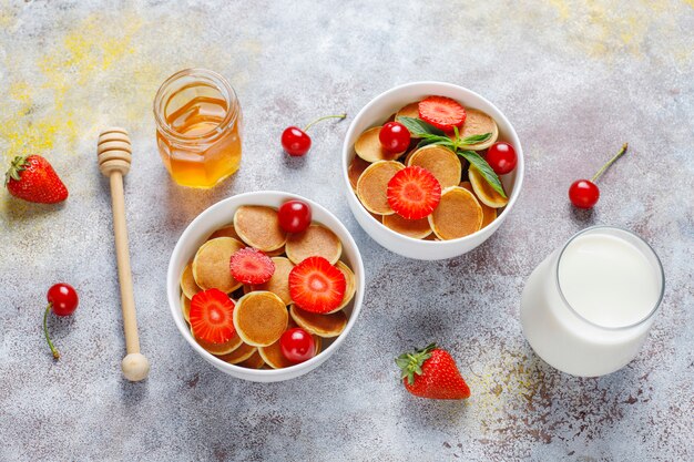 Comida de moda: mini cereal para panqueques. Montón de panqueques de cereales con bayas y nueces.