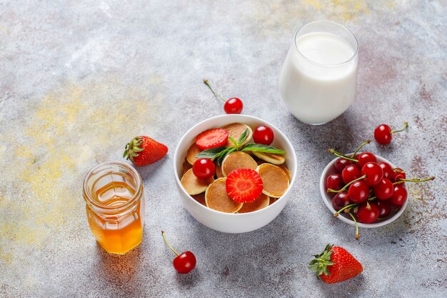 Comida de moda: mini cereal para panqueques. Montón de panqueques de cereales con bayas y nueces.