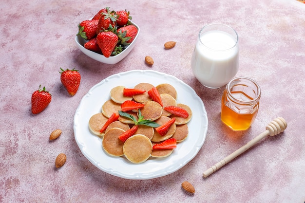 Comida de moda: mini cereal para panqueques. Montón de panqueques de cereales con bayas y nueces.