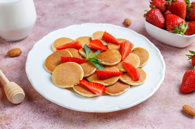 Comida de moda: mini cereal para panqueques. Montón de panqueques de cereales con bayas y nueces.